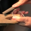 Hands filing a silver bangle on a jewellers peg
