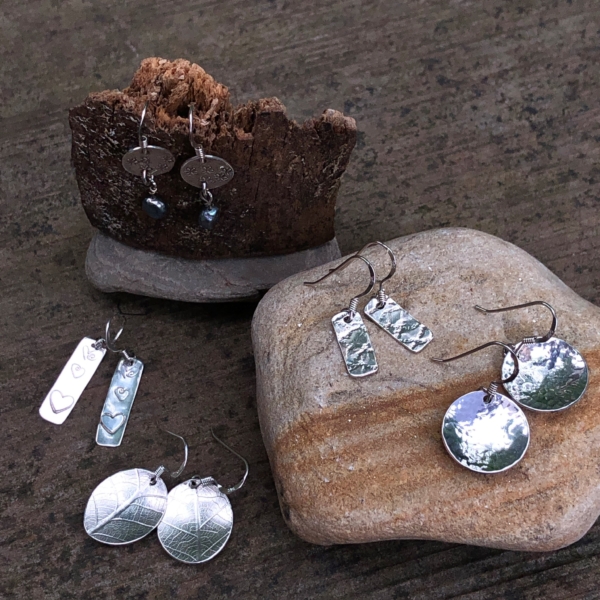 silver dangly earrings on stone and bark background