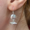 Silver dangly earring with bird stamp being worn.