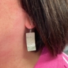Silver dangly earring being worn with pink top
