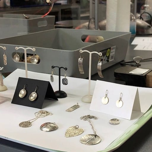 Silver jewellery examples on a tray in the workshop