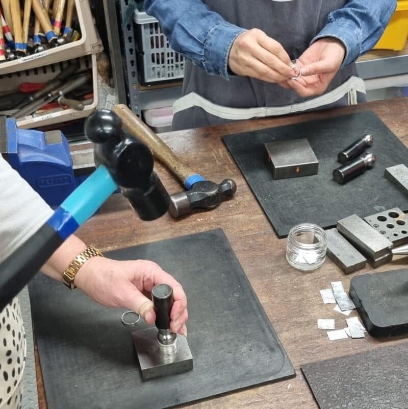 students hammering their spinner rings at the workbench