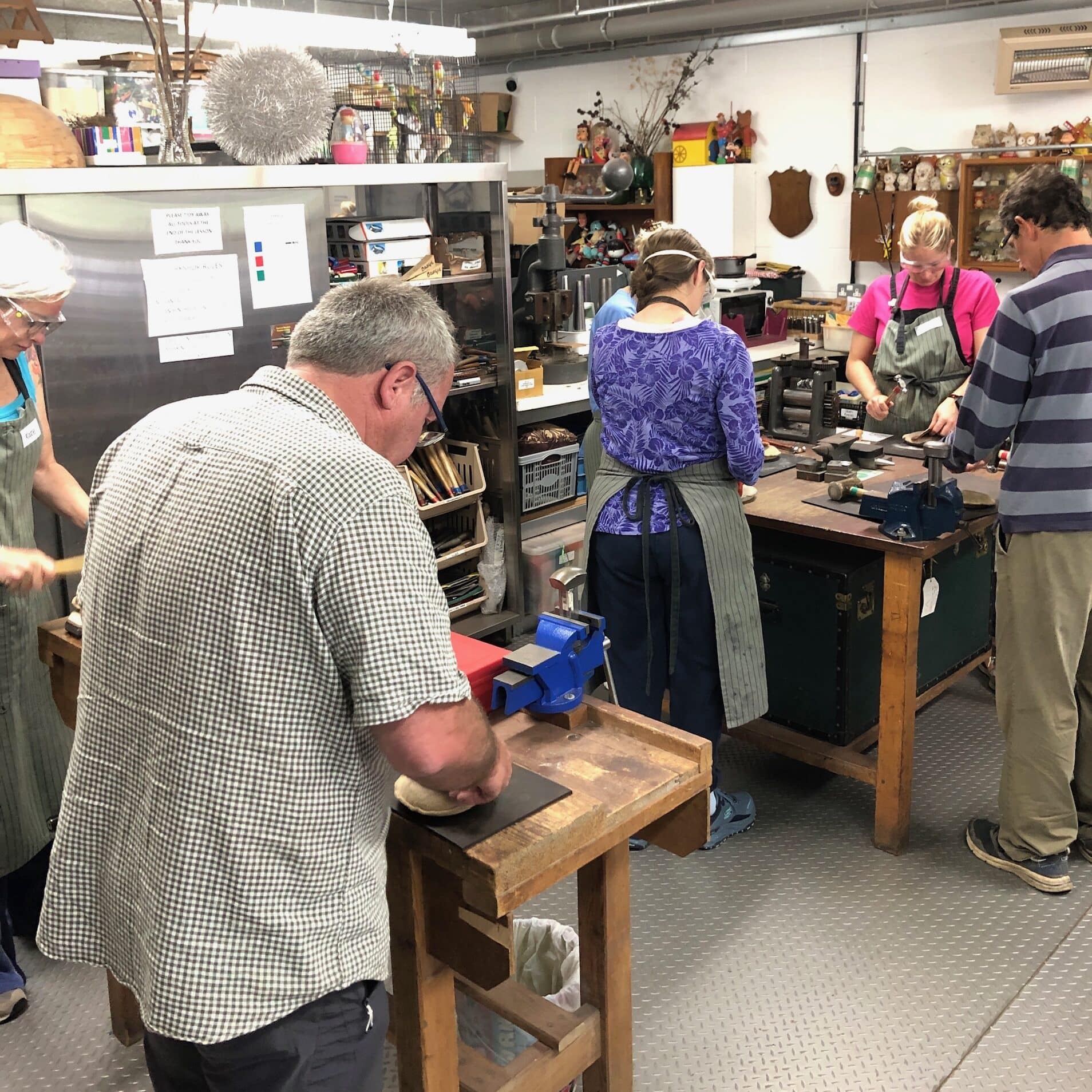 Students hammering copper bowls in the workshop