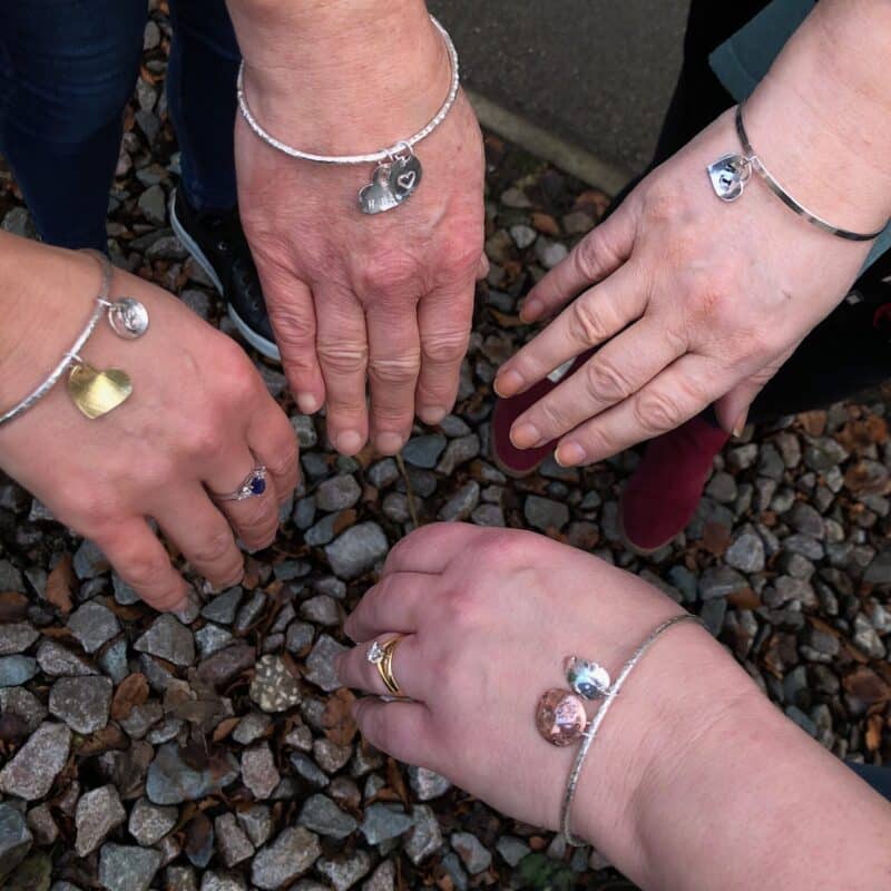 Silver charm bangles being worn