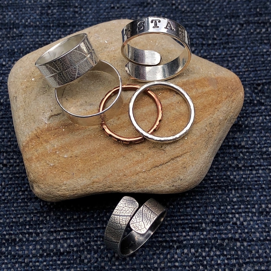 silver and copper rings on stone and blue background
