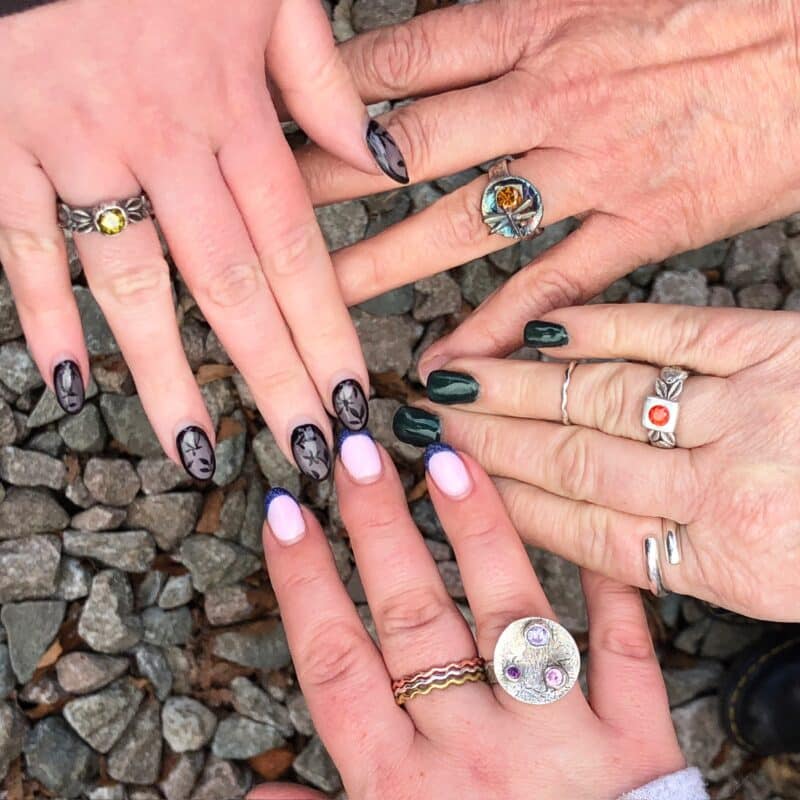 Four hands in a circle wearing finished silver clay rings