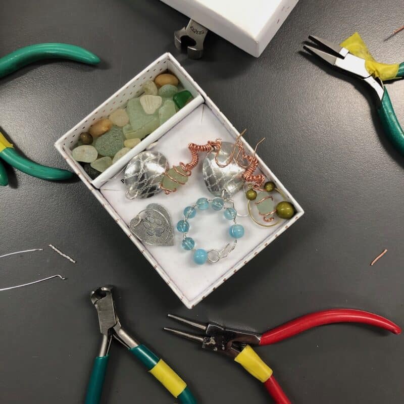 Box of found sea glass and new pieces of jewellery with pliers and wire cutters