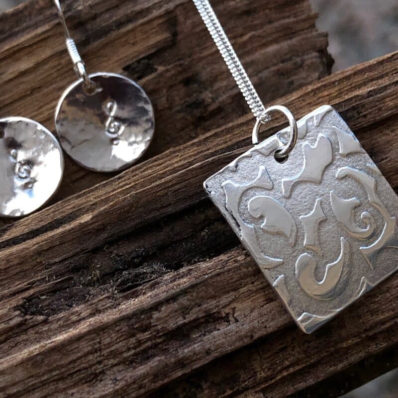 Silver pendant with swirly texture and earrings with musical note stamp