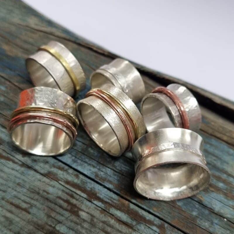 Silver spinner rings with mixed metal spinners on blue background