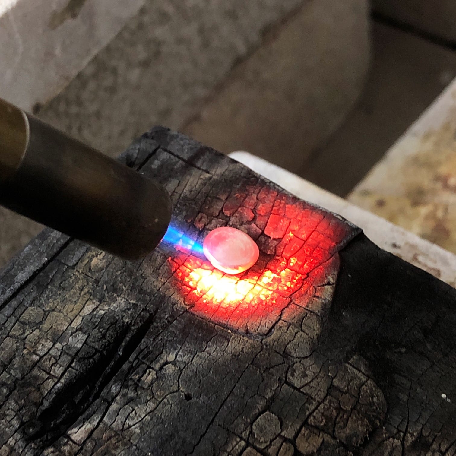 Melting scrap silver with a flame on a charcoal block