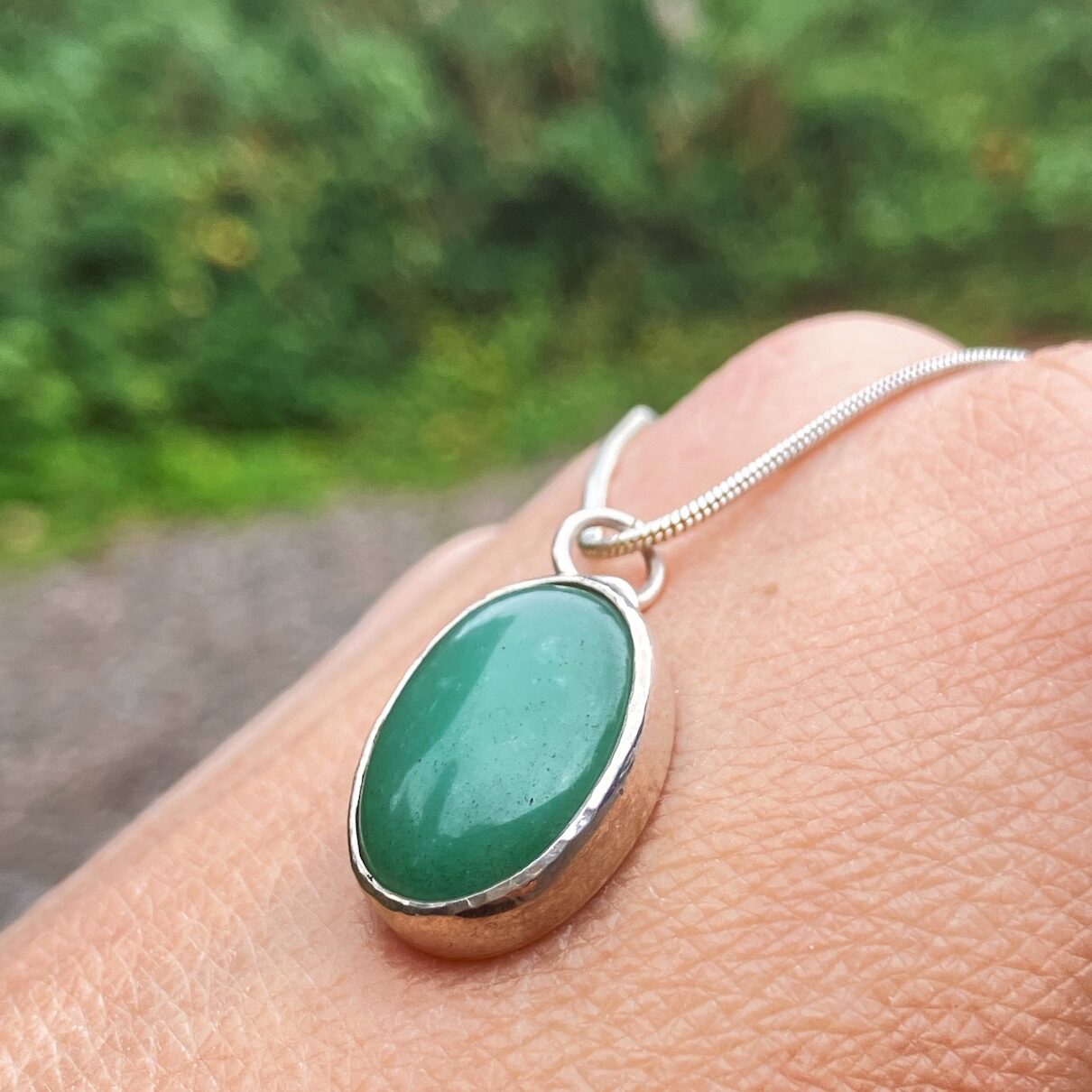 Bezel set pendant with green stone on a silver chain