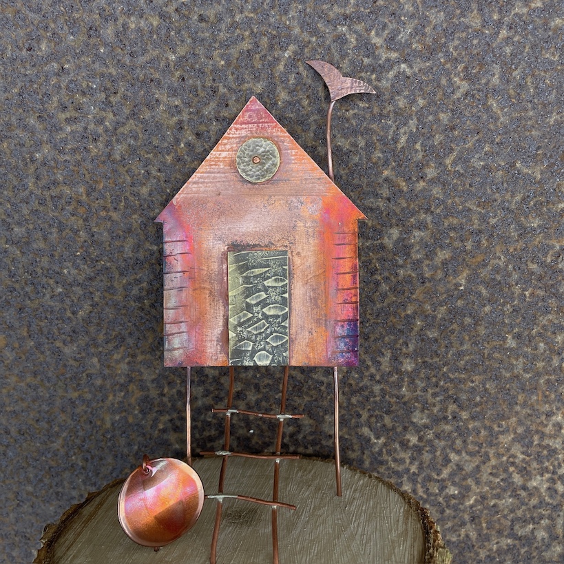 Mini mixed metal beach hut sculpture on wooden plinth
