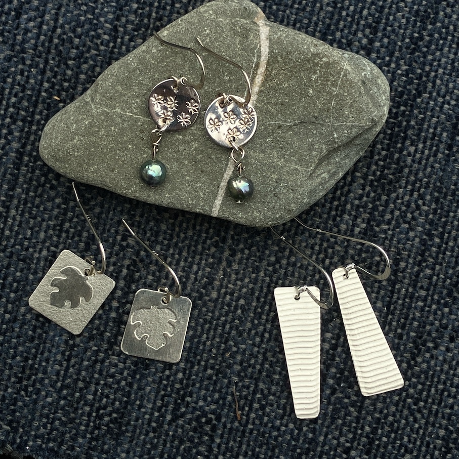 Silver earrings on stone and blue background